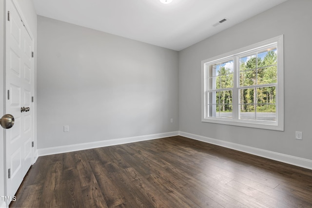 empty room featuring visible vents, baseboards, and dark wood-style flooring