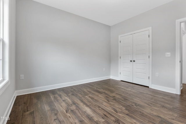 unfurnished bedroom with a closet, baseboards, and dark wood finished floors