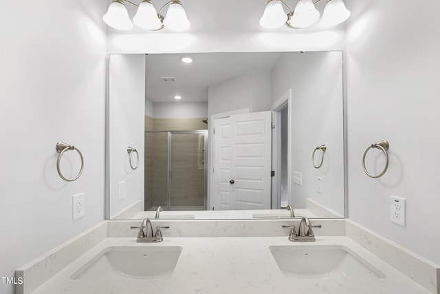 full bath featuring double vanity, a notable chandelier, a shower stall, and a sink