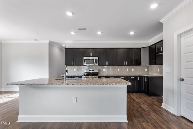 kitchen featuring light stone counters, visible vents, an island with sink, a sink, and stainless steel appliances