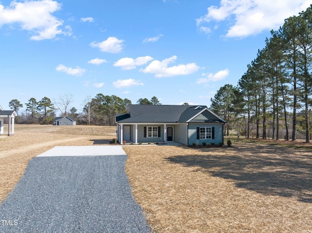 view of front of property featuring covered porch, driveway, and a front lawn