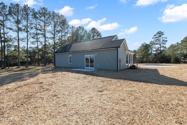 back of property featuring a shingled roof and a patio