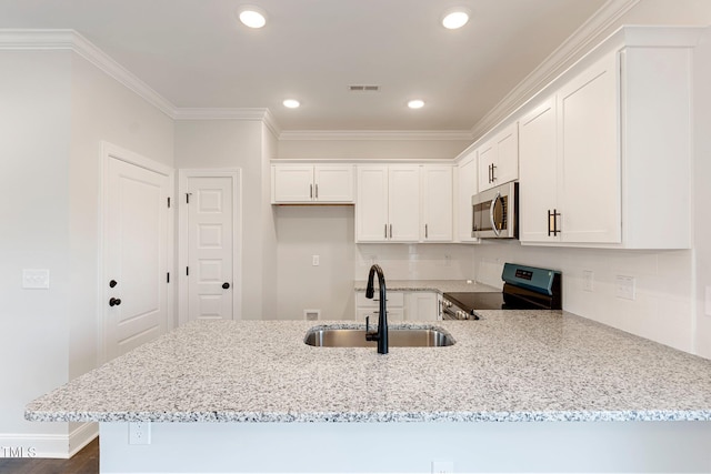 kitchen with light stone countertops, ornamental molding, appliances with stainless steel finishes, a peninsula, and a sink