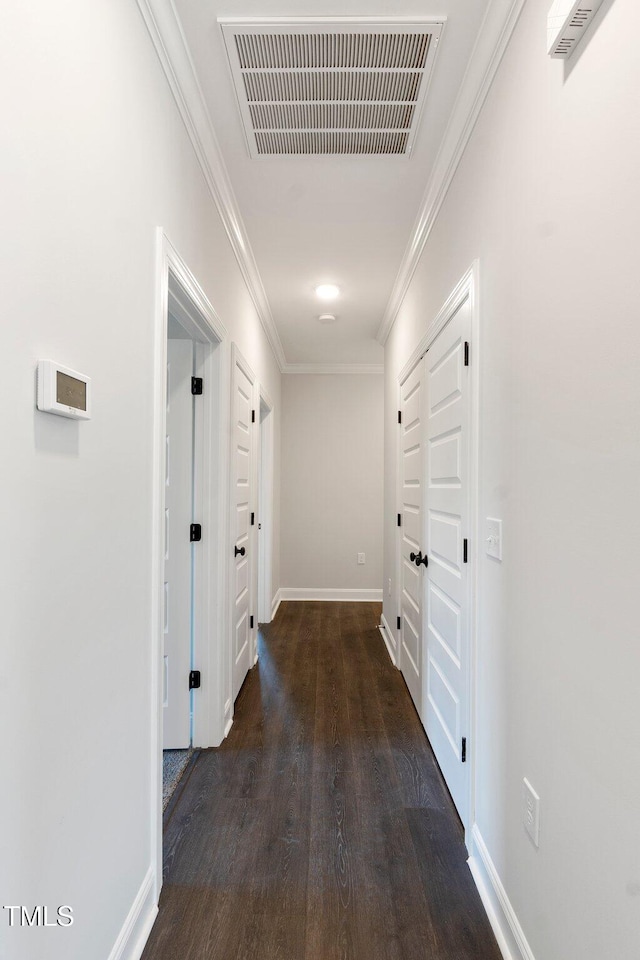 hall featuring visible vents, wood finished floors, baseboards, and ornamental molding