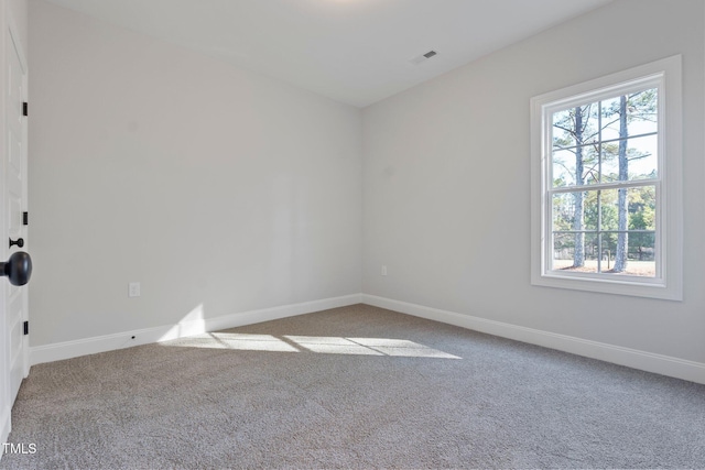 empty room featuring carpet, visible vents, and baseboards