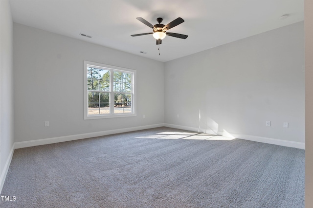 carpeted spare room featuring a ceiling fan, visible vents, and baseboards