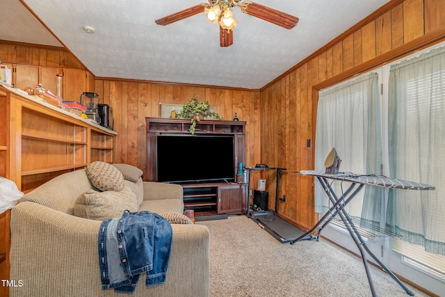 carpeted living room featuring wooden walls, a textured ceiling, crown molding, and a ceiling fan