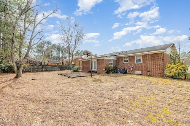 rear view of house with a patio, fence, brick siding, and central AC