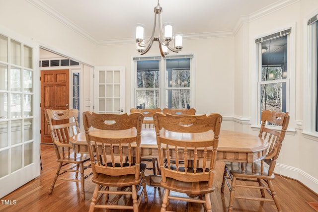 dining room featuring wood finished floors, a healthy amount of sunlight, a chandelier, and ornamental molding