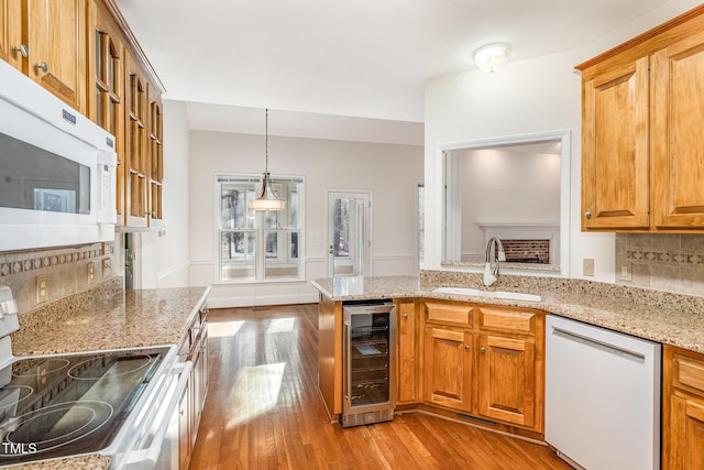 kitchen featuring white appliances, a sink, decorative backsplash, wine cooler, and light wood-style floors