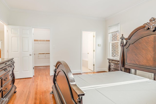 bedroom with ornamental molding, a closet, light wood finished floors, baseboards, and a spacious closet