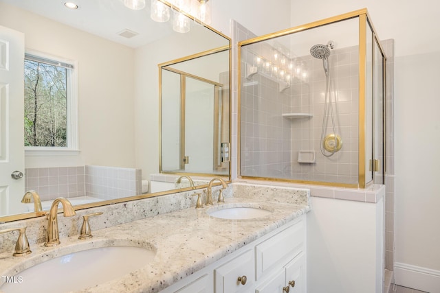 full bath featuring a sink, visible vents, a stall shower, and double vanity