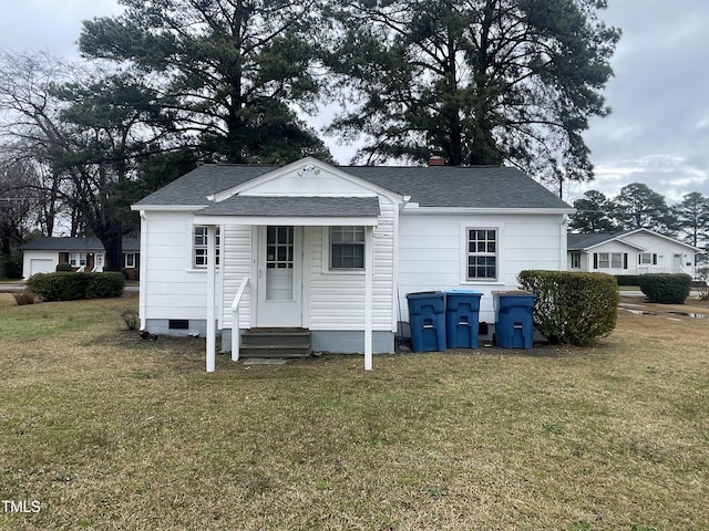 rear view of property featuring crawl space, a lawn, a shingled roof, and entry steps