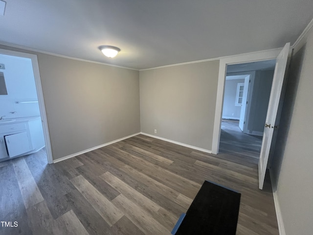 unfurnished room with dark wood-style flooring, baseboards, and ornamental molding