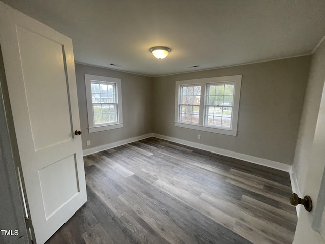 spare room with visible vents, crown molding, dark wood-type flooring, and baseboards