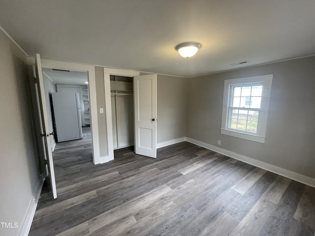 unfurnished bedroom with visible vents, freestanding refrigerator, baseboards, and dark wood-style flooring