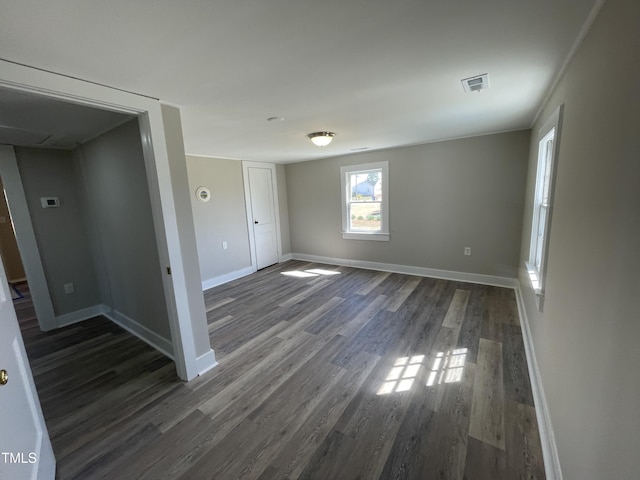 spare room featuring dark wood-style floors, visible vents, and baseboards