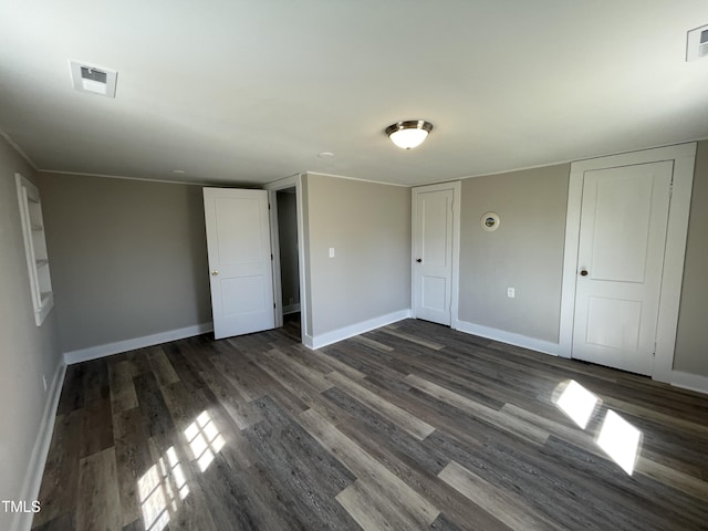 unfurnished bedroom featuring visible vents, baseboards, and dark wood-style flooring