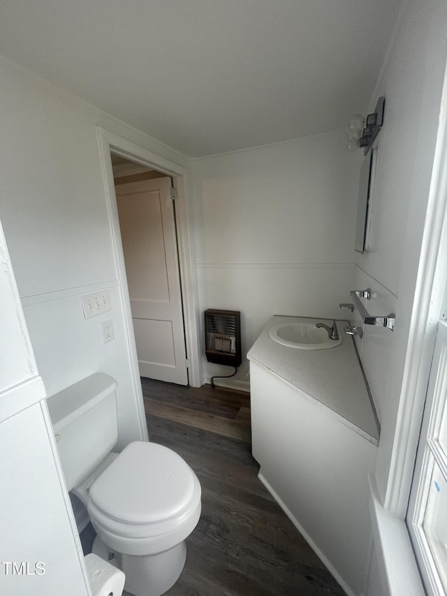 bathroom with heating unit, toilet, vanity, and wood finished floors