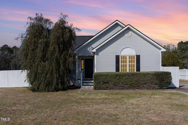 view of front of home featuring fence and a lawn