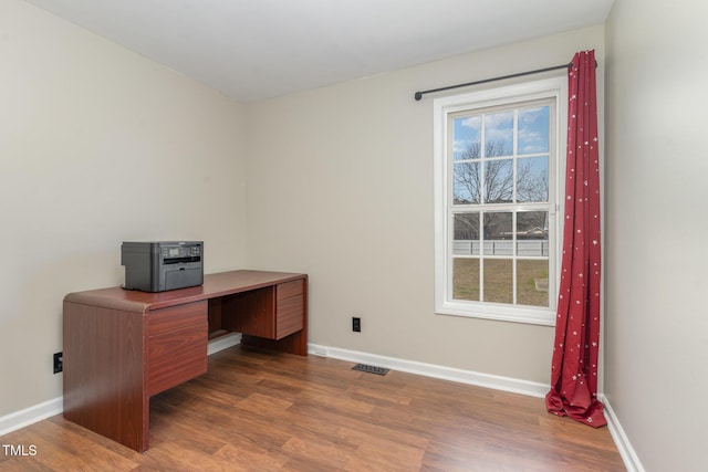 home office with plenty of natural light, baseboards, visible vents, and wood finished floors