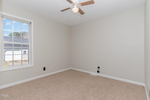 carpeted spare room with visible vents, baseboards, and ceiling fan