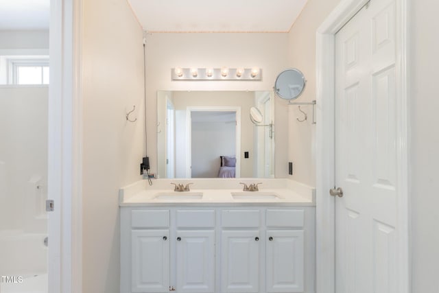 ensuite bathroom with double vanity, ensuite bath, and a sink