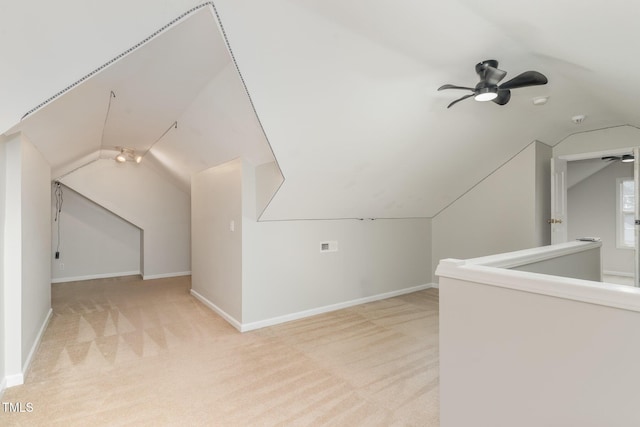 additional living space with light colored carpet, a ceiling fan, lofted ceiling, and baseboards