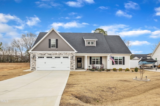 view of front facade with stone siding, covered porch, concrete driveway, an attached garage, and a shingled roof