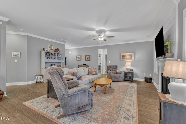 living area featuring baseboards, wood finished floors, a ceiling fan, and crown molding