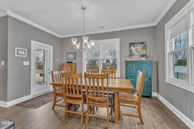 dining room featuring an inviting chandelier, wood finished floors, baseboards, and ornamental molding