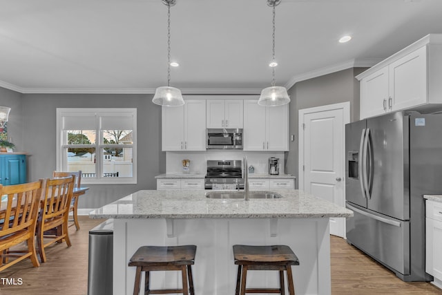 kitchen featuring ornamental molding, a sink, white cabinets, light wood-style floors, and appliances with stainless steel finishes