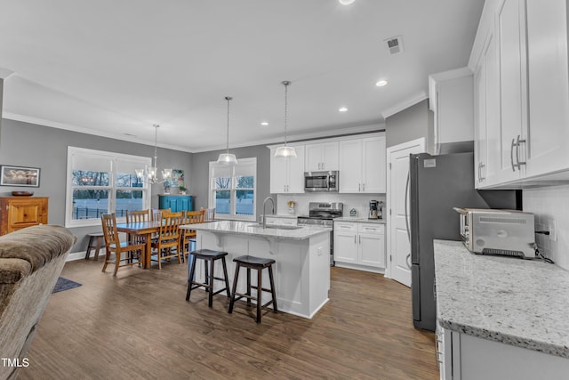 kitchen featuring visible vents, ornamental molding, a sink, white cabinetry, and stainless steel appliances