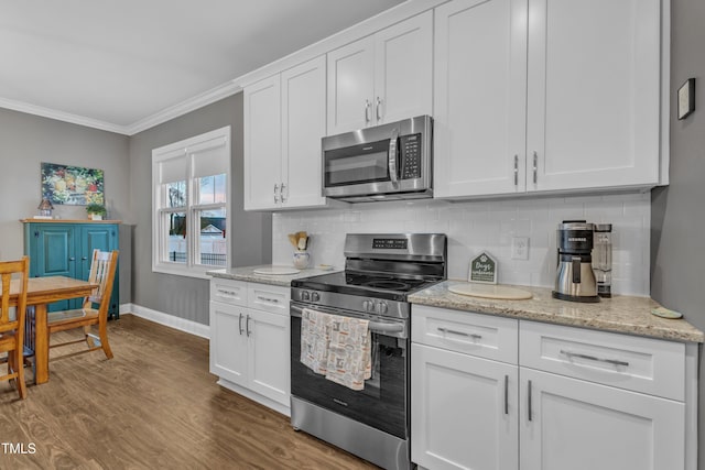 kitchen featuring backsplash, crown molding, appliances with stainless steel finishes, wood finished floors, and white cabinets