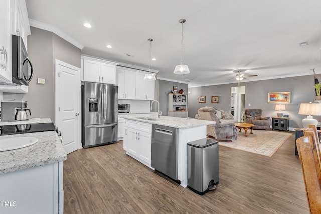 kitchen featuring open floor plan, appliances with stainless steel finishes, crown molding, and a sink