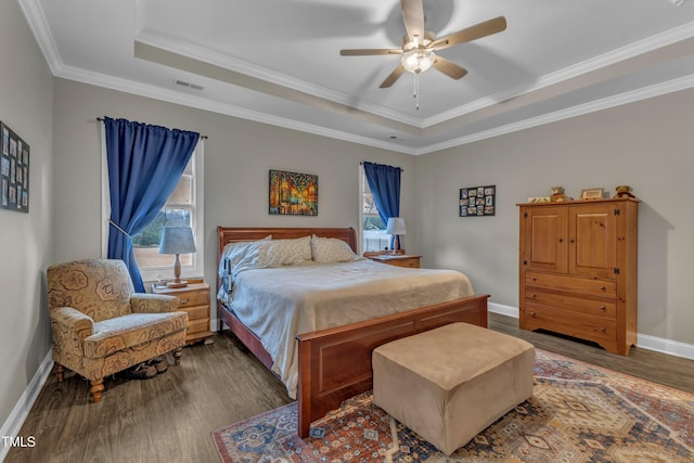 bedroom featuring a tray ceiling, multiple windows, baseboards, and wood finished floors