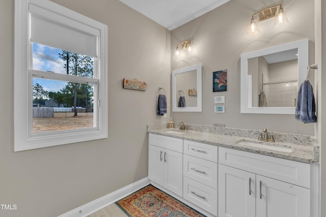 full bath featuring double vanity, baseboards, and a sink