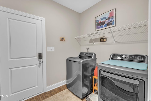 laundry area featuring washer and dryer, baseboards, wood finished floors, and laundry area