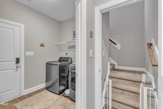 washroom featuring washer / dryer, wood finished floors, baseboards, and laundry area