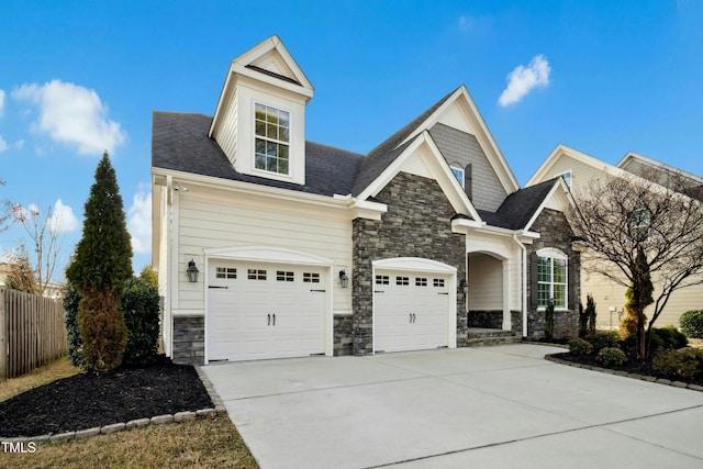 view of front of home featuring a garage, stone siding, driveway, and fence