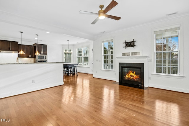 unfurnished living room with visible vents, light wood-style flooring, and ornamental molding