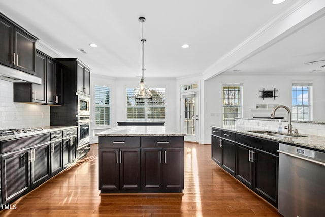 kitchen with dark wood-style flooring, ornamental molding, stainless steel appliances, and a sink