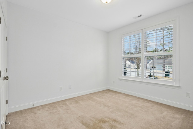 unfurnished room with baseboards, visible vents, and light carpet