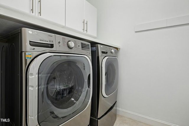 clothes washing area with cabinet space, light tile patterned floors, washing machine and dryer, and baseboards