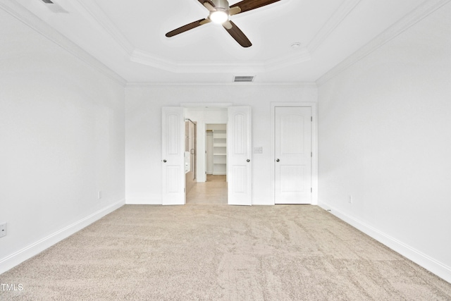 unfurnished bedroom with a raised ceiling, carpet flooring, visible vents, and ornamental molding