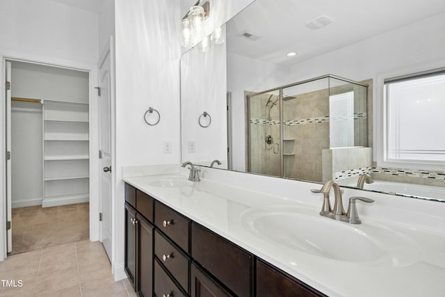 bathroom featuring a sink, double vanity, a shower stall, and tile patterned flooring