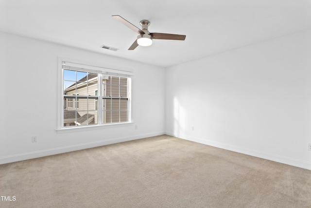 spare room with visible vents, carpet floors, baseboards, and a ceiling fan