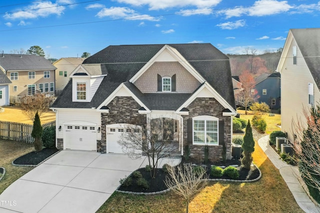 view of front facade featuring fence, driveway, roof with shingles, a garage, and stone siding