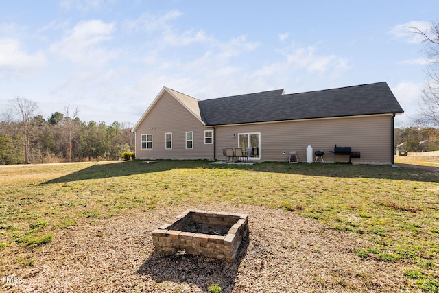 rear view of house with a lawn and an outdoor fire pit