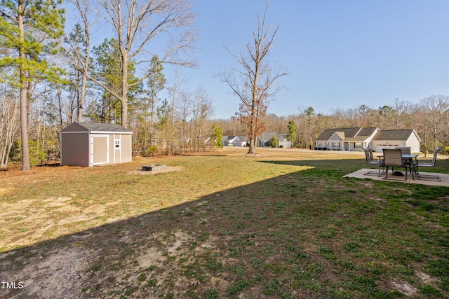 view of yard featuring a storage unit, an outdoor structure, and a patio area